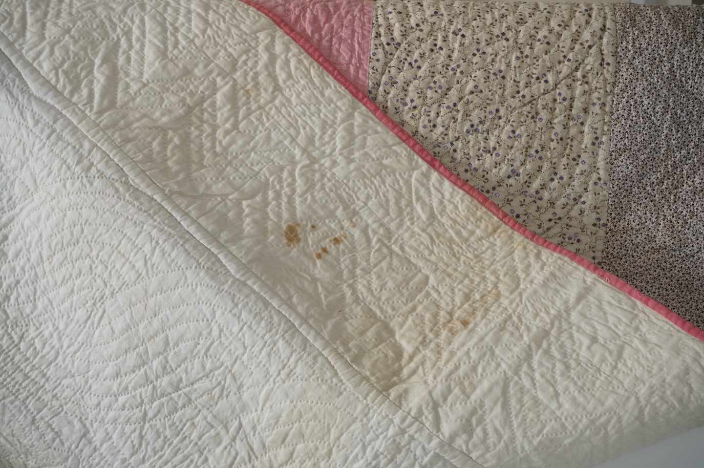 An English 19th century, highly ornate hand quilted English bedcover. Designed using alternating stripes, in a plain pink and a small printed floral cotton, then finishing with two borders of a darker minute spot floral